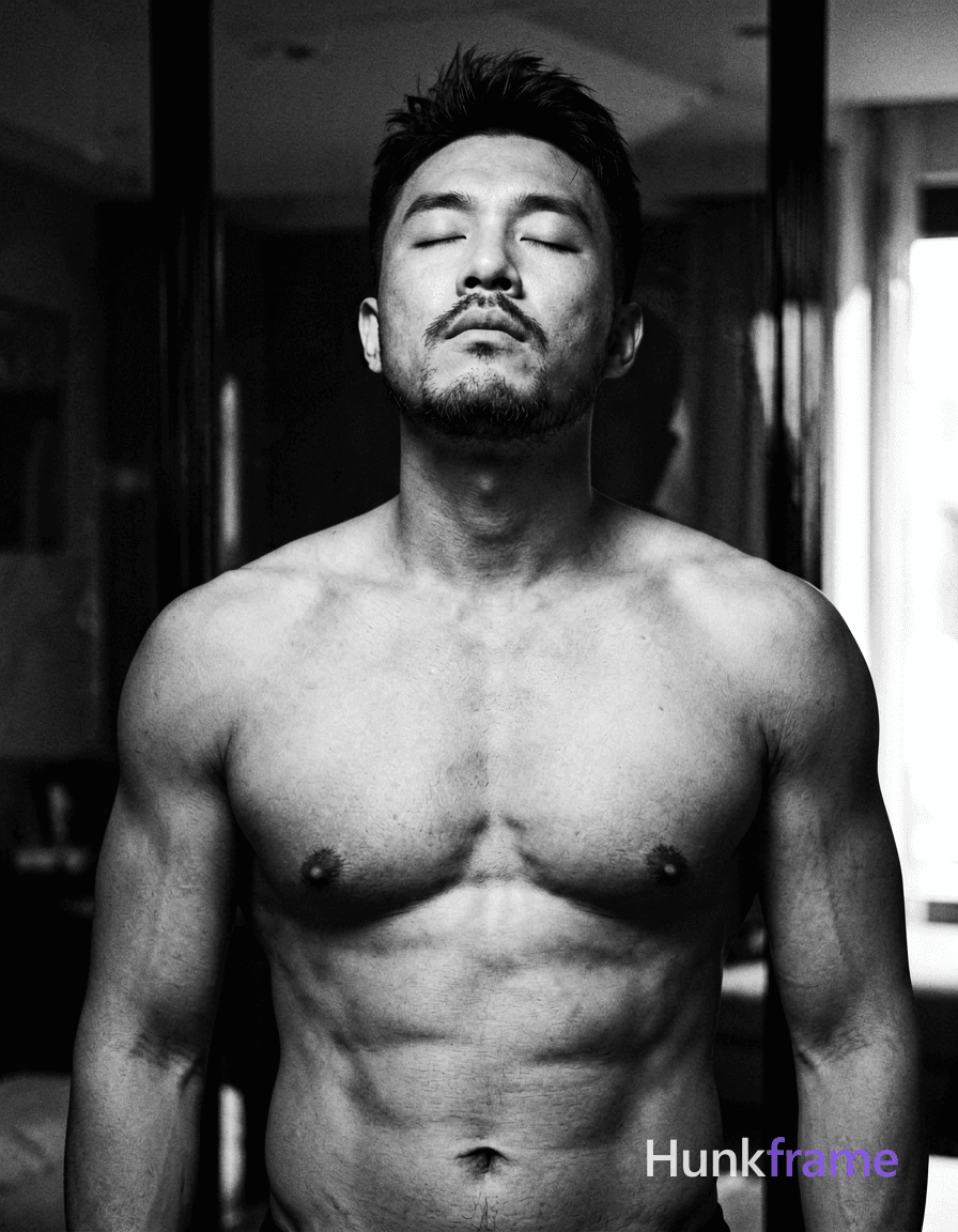 An Asian man with medium-dark skin and a dark, short hairstyle styled upward stands shirtless in