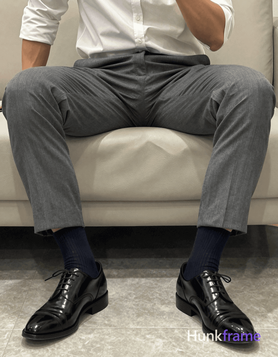 Photoreal photograph of a seated man in a torso-only crop. He is wearing gray suit pants, a white dr